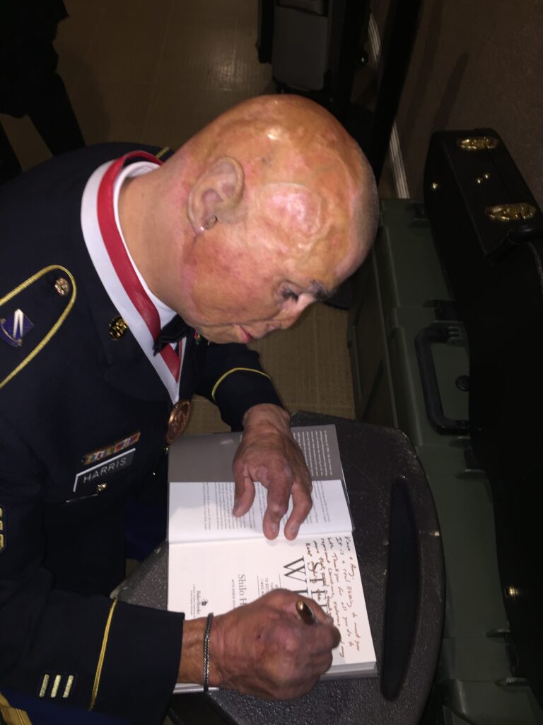 Picture of Shilo Harris signing his book at an Allied Health event